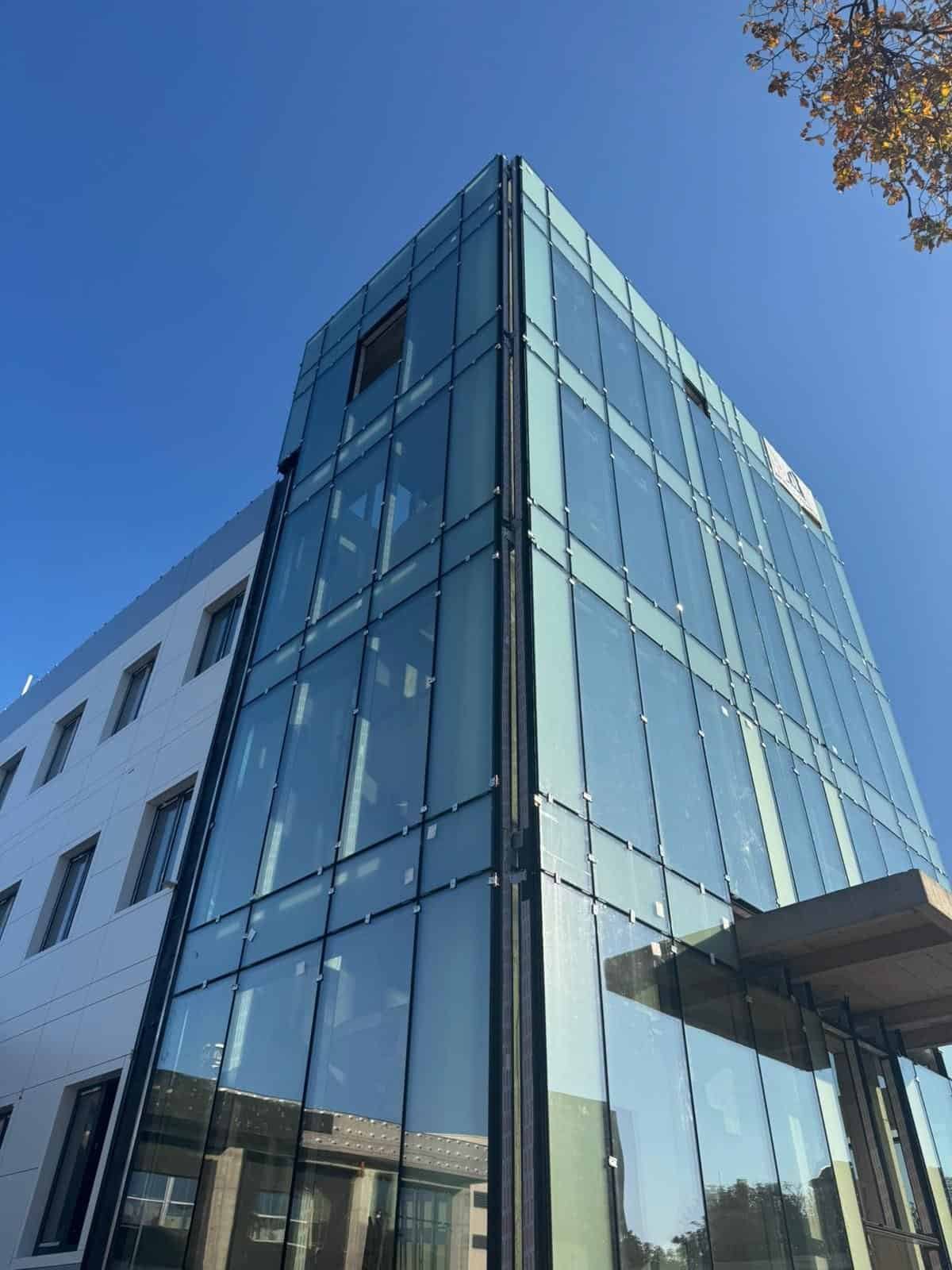 Imagine cu fațada din sticlă a unei clădiri moderne, evidențiind serviciile de montaj sticlă oferite.